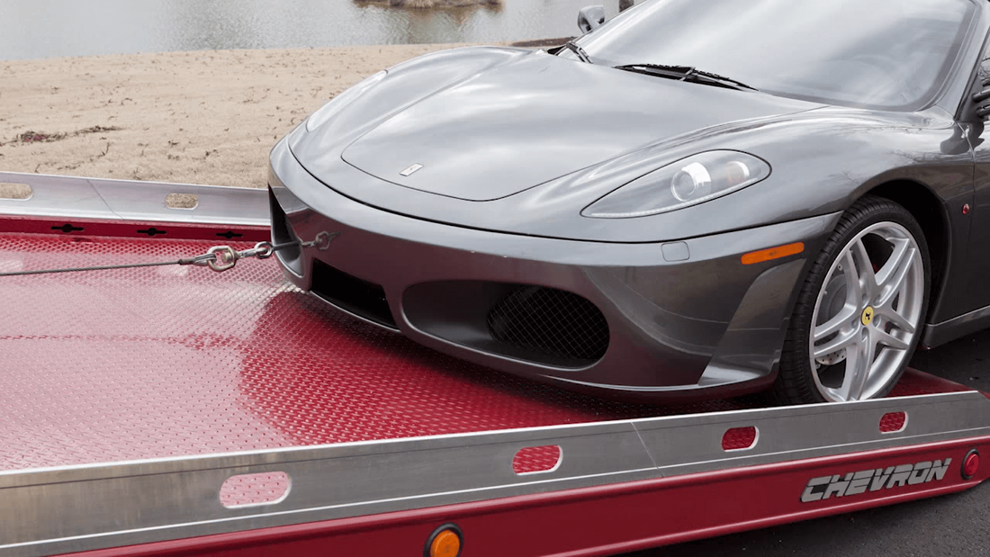 Gray Ferrari being pulled onto red flatbed tow truck