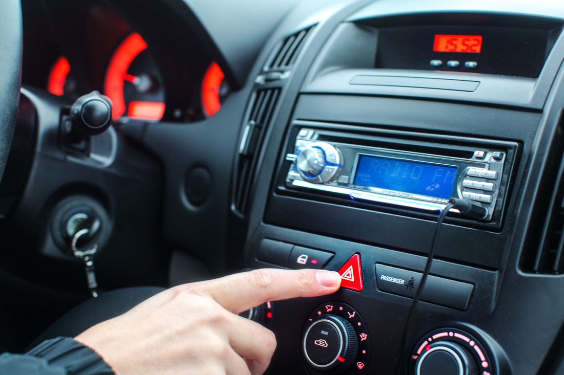 Woman in car pressing emergency hazard lights or flasher button on the center console of her car