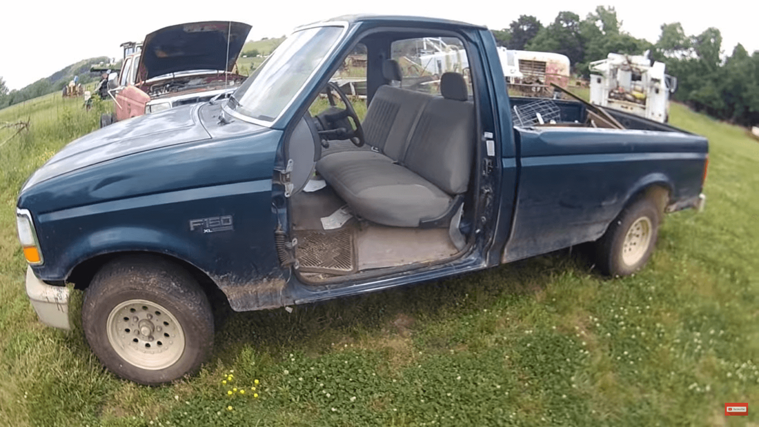 Old junk Ford F-150 pickup truck on grass on large property
